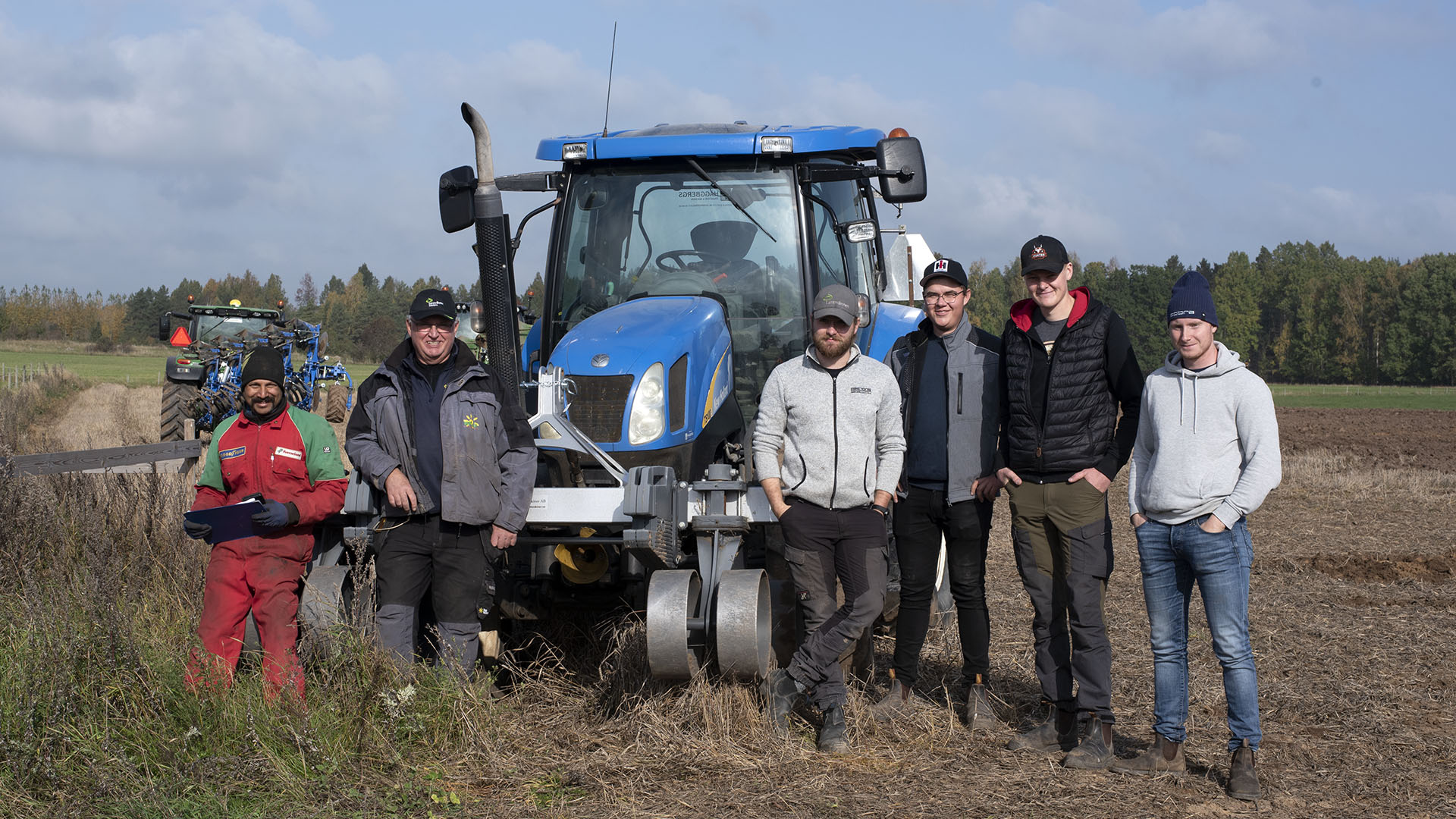 Ett team med testförare på fält framför en blå traktor